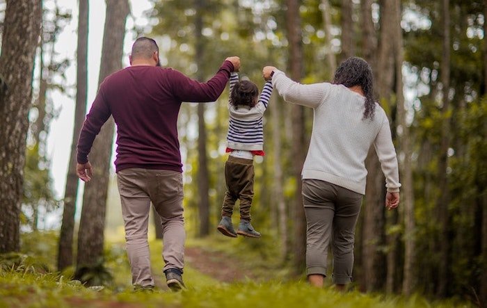 Couple carrying a child through the woods during outdoor therapy at a drug and alcohol rehab centre in Glasgow