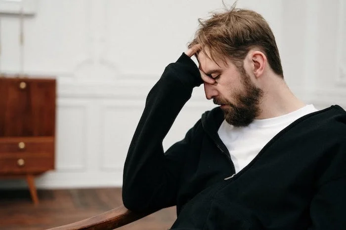 Man holding his head suffering from symptoms of PTSD and substance use disorder